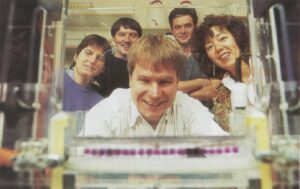 Peter Harris with 4 team members behind him in the lab. 